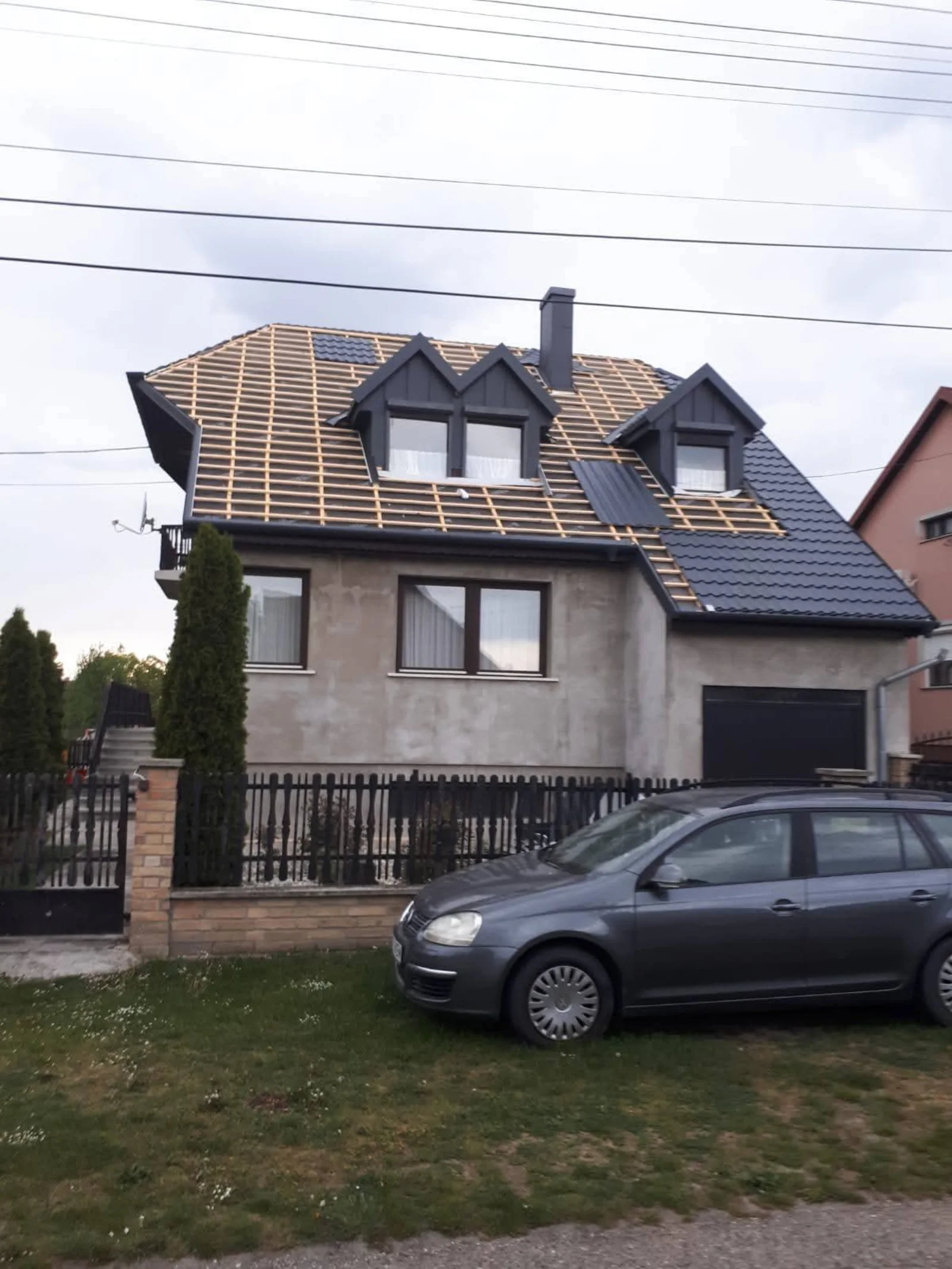 Casă cu acoperiș antracit, două lucarne și panouri solare