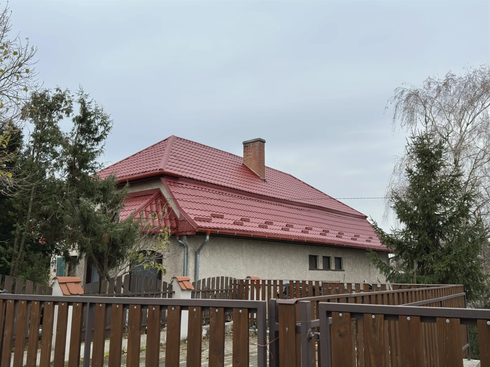 Casă cu acoperiș din țiglă roșie, văzută din curte
